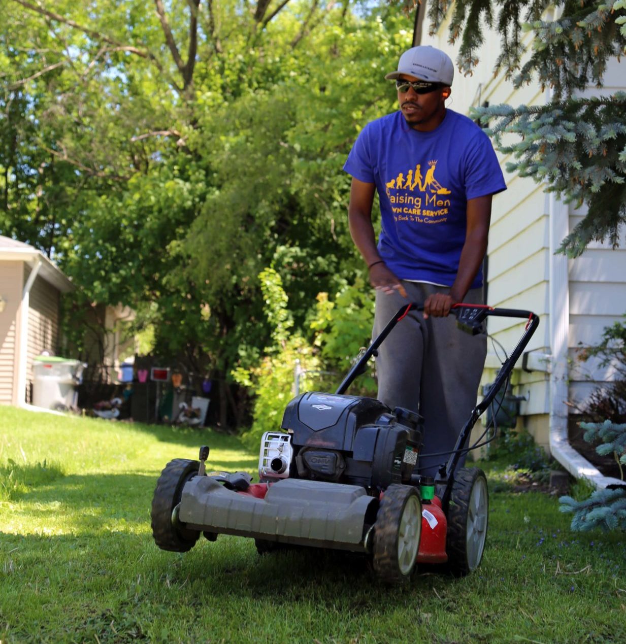 A man with a lawnmower wearing a custom t-shirt.