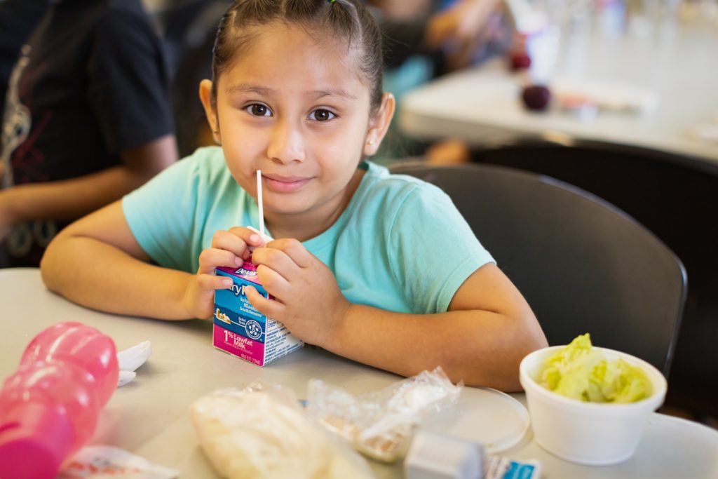 A 6-year old schoolkid eating lunch at a summer meals program