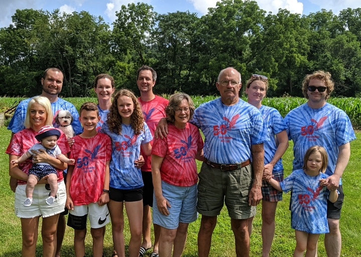 A whole family including dogs show off their red and blue tie-dyed shirts.