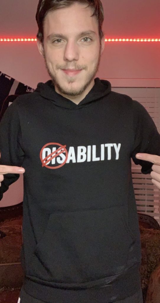 Jacob pointing to the design on his disABILITY hoodie