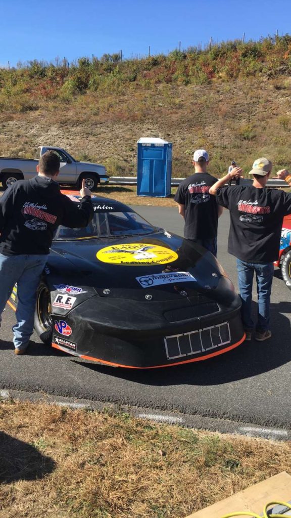 Photo of a car team showing off the back of their matching shirts