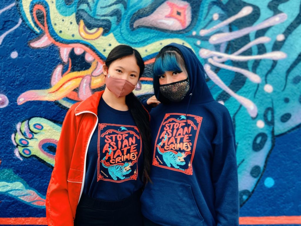 Lauren and a friend wearing Stop Asian Hate Crimes apparel in front of the Stop Asian Hate Crimes mural