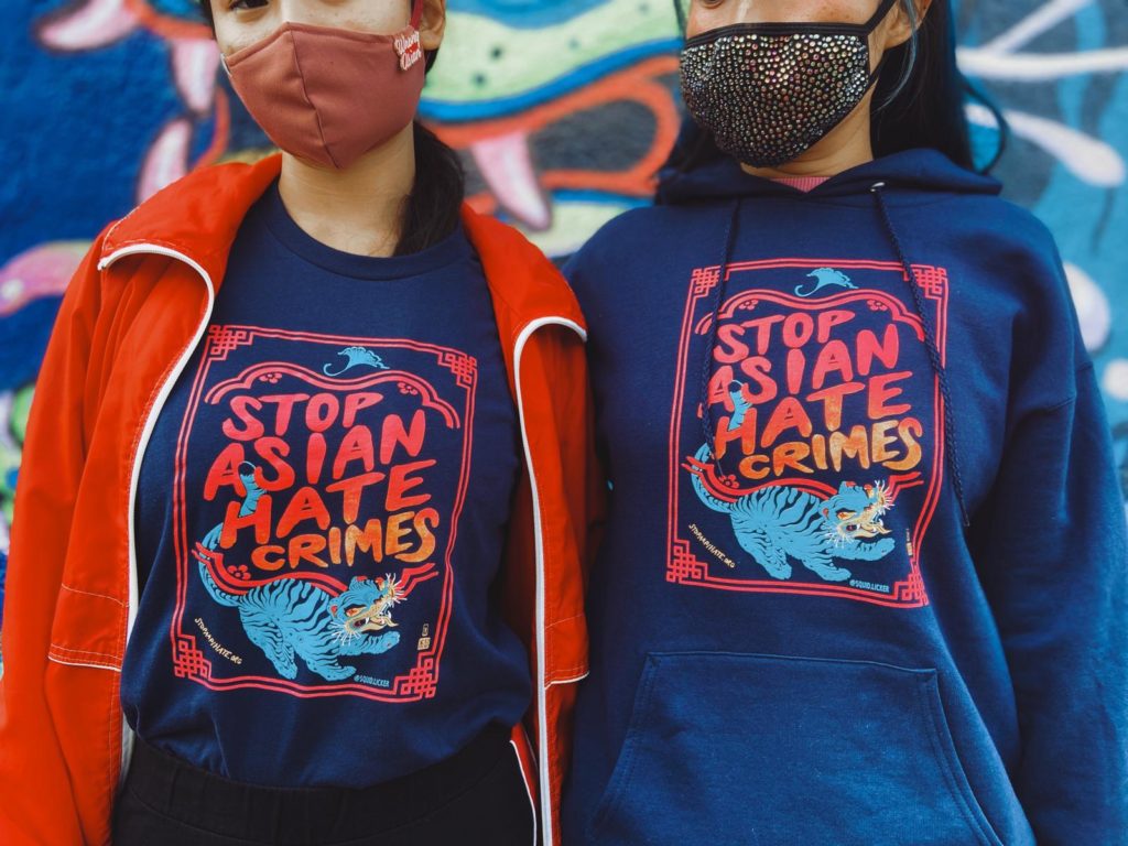 Close-up photo of Lauren and a friend wearing Stop Asian Hate Crimes apparel in front of the Stop Asian Hate Crimes mural