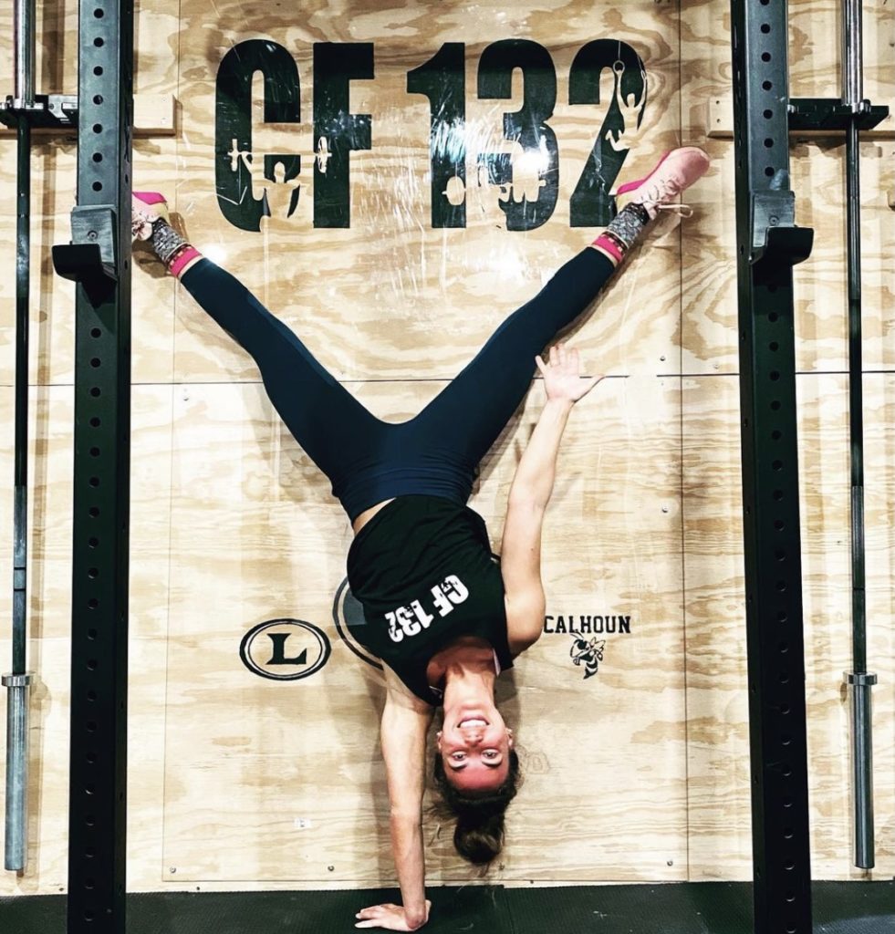Woman doing a one-handed handstand in a CF 132 tank