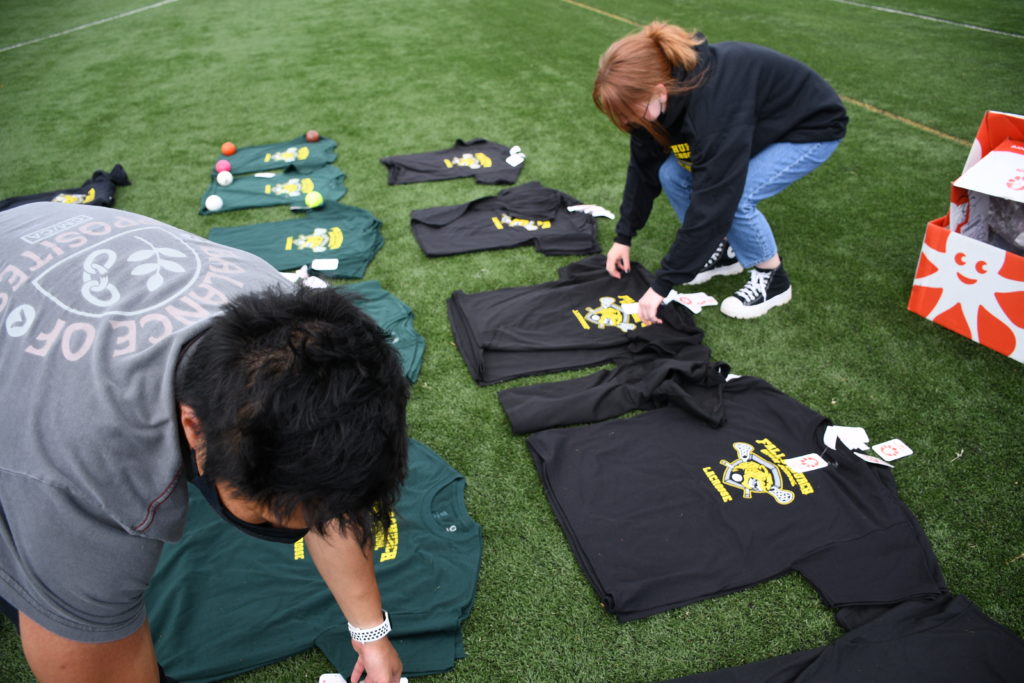 Two people lying out the custom t-shirts on the grass.