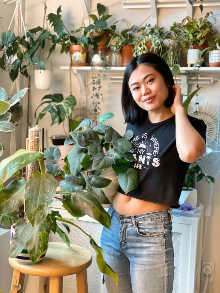 Woman surrounded by plants wearing a cropped t-shirt