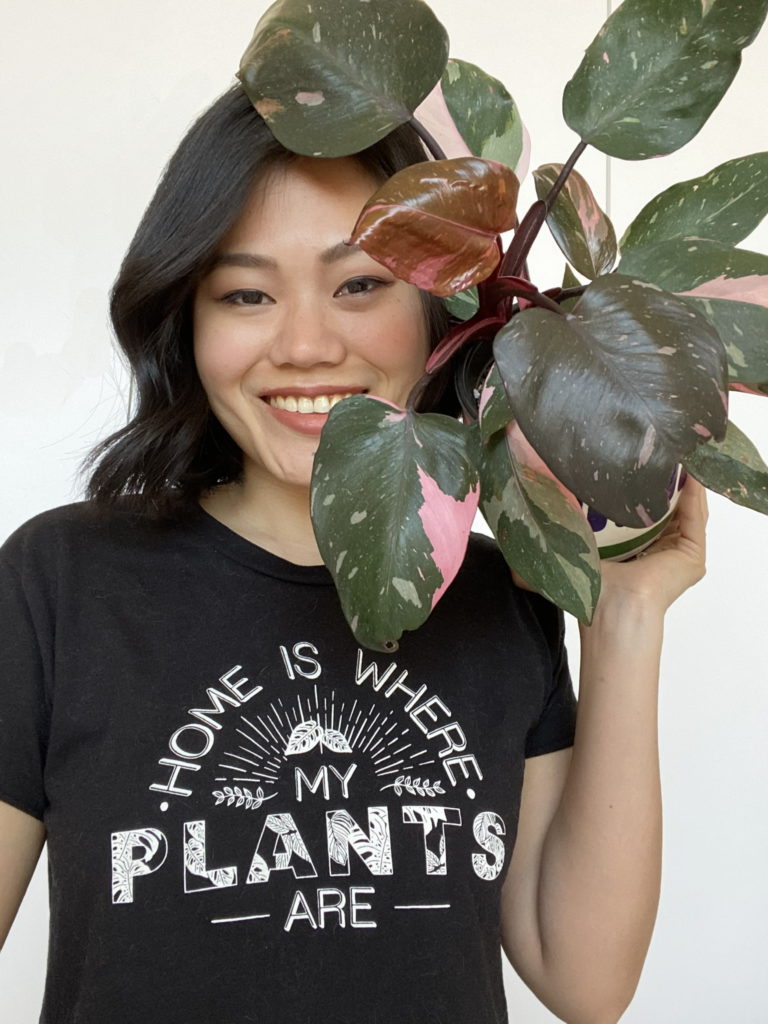 Woman holding a plant and wearing a black shirt with Home is Where My Plants Are shirt