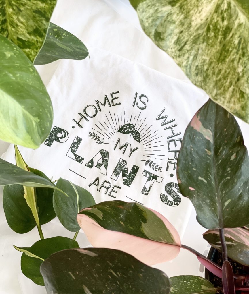 A folded shirt with Home is Where My Plants Are printed in green