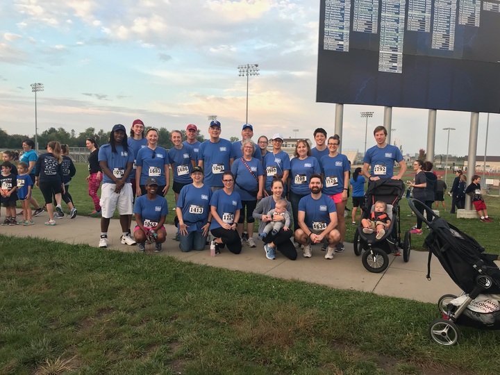 Group of runners wearing matching blue team shirts standing in front of a field