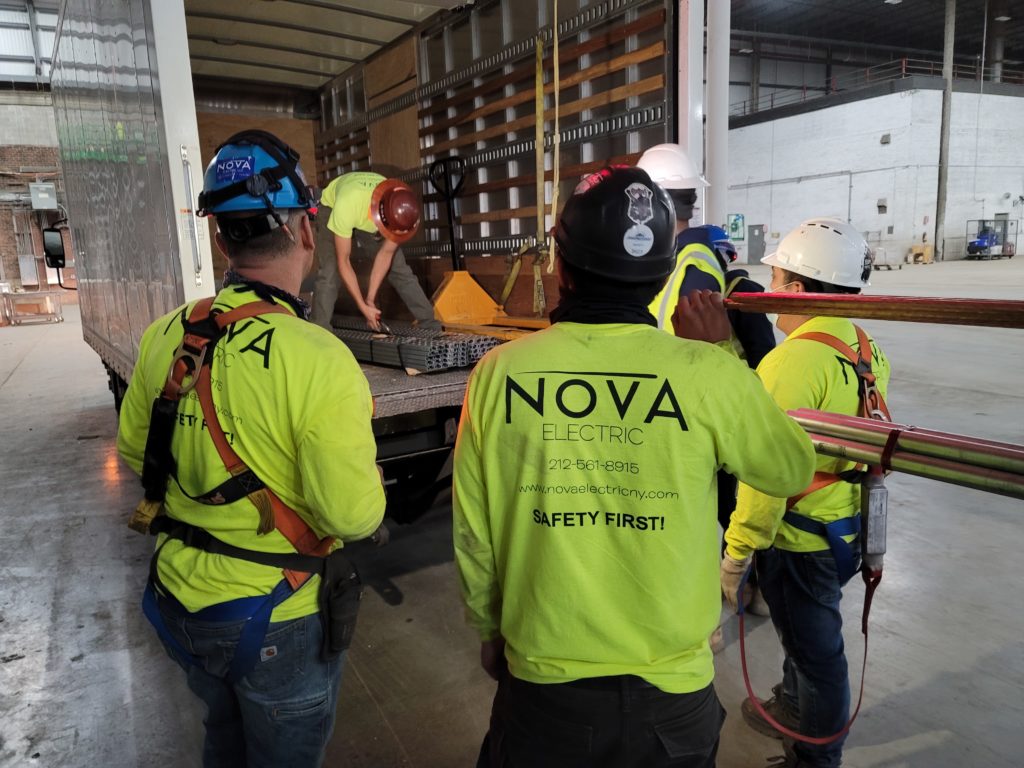 Multiple contractor workers helping load equipment while wearing matching neon green Nova Electric shirts