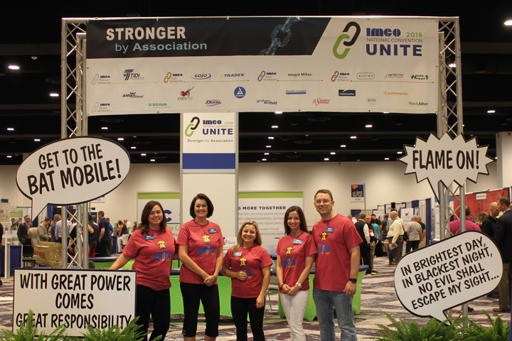 A trade show group shows off their custom t-shirts at an exhibition.