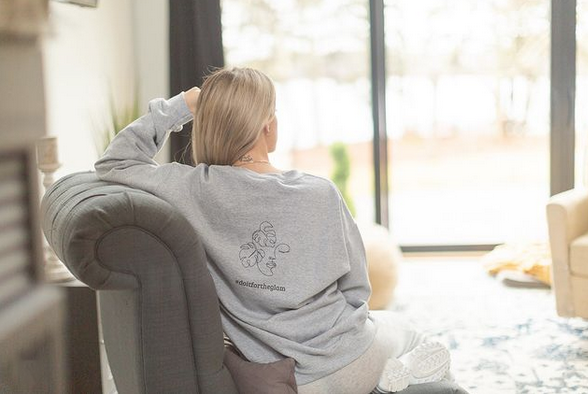 Woman sitting on a couch wearing a custom sweatshirt with her back to the camera