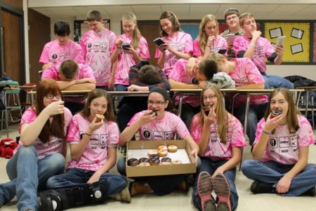 A group of students enjoying a box of donuts in their matching custom t-shirts.