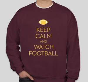 A maroon crewneck sweatshirt with yellow text that reads "Keep calm and watch football." A yellow football is at the top. 