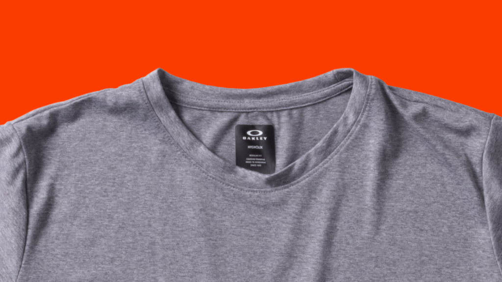 A close-up of a gray Oakley Team Issue Hydrolix Performance Shirt from the shoulders up. This shirt has a silky and stretchy look and feel. 