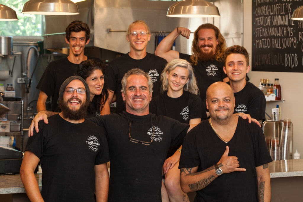 A group of people wearing their deli custom gear in their kitchen. 