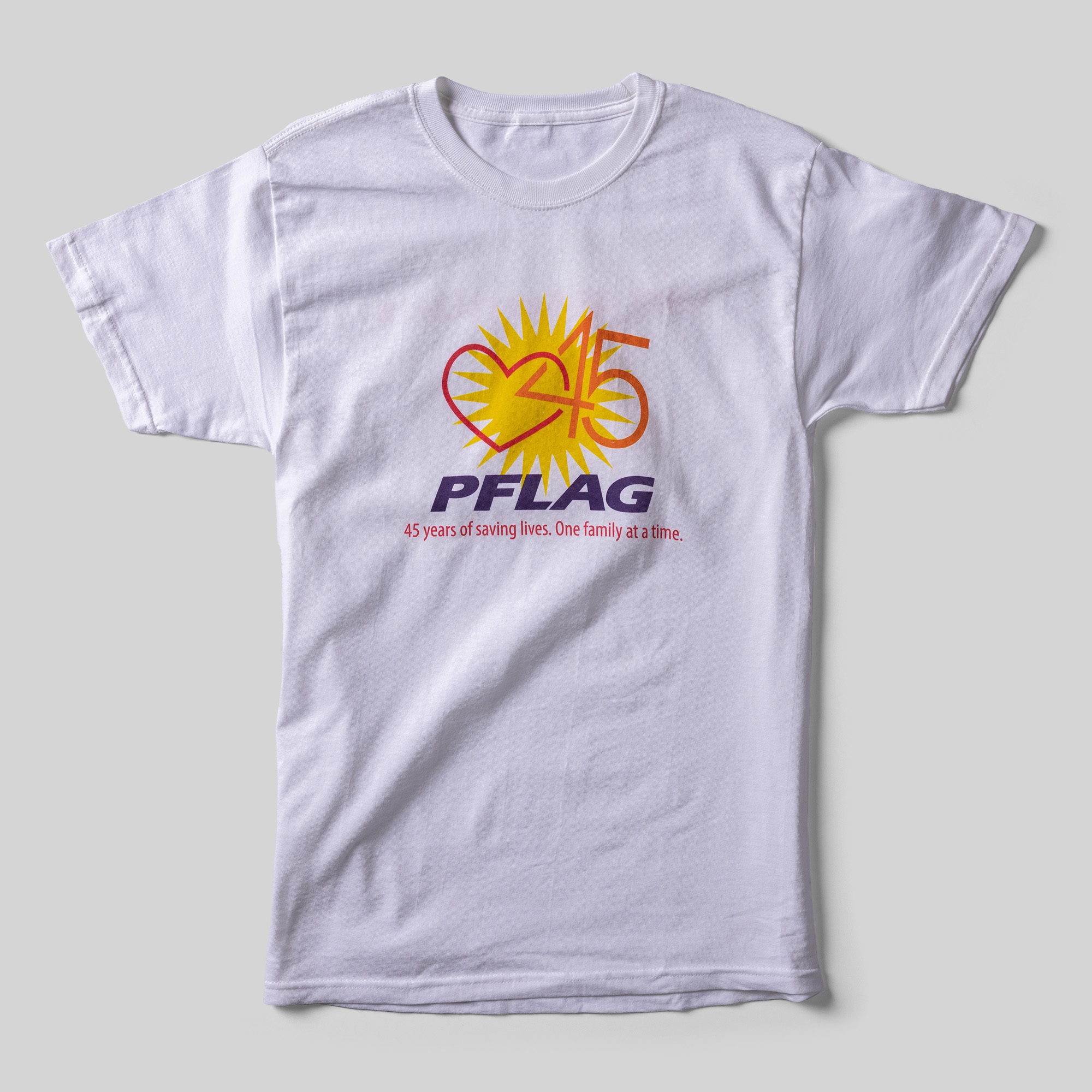 A white t-shirt that reads "PFLAG 45 years of saving lives. One family at a time." An illustration of 45 linked with a heart in front of a sun is above the text.