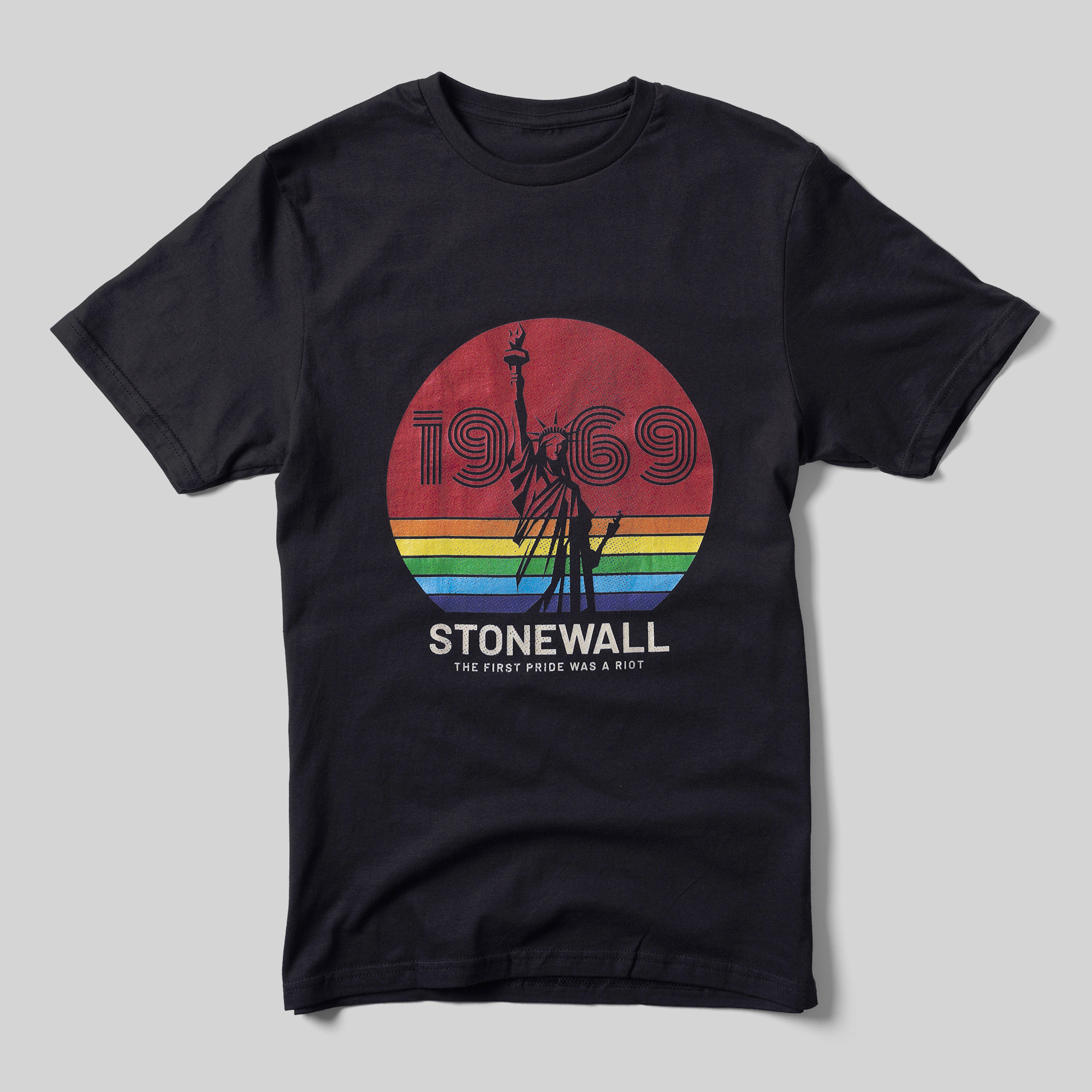 A black t-shirt that reads "1969" inside of a rainbow-colored circle with a black illustration of the Statue of Liberty. Beneath that reads "Stonewall The First Pride Was a Riot."