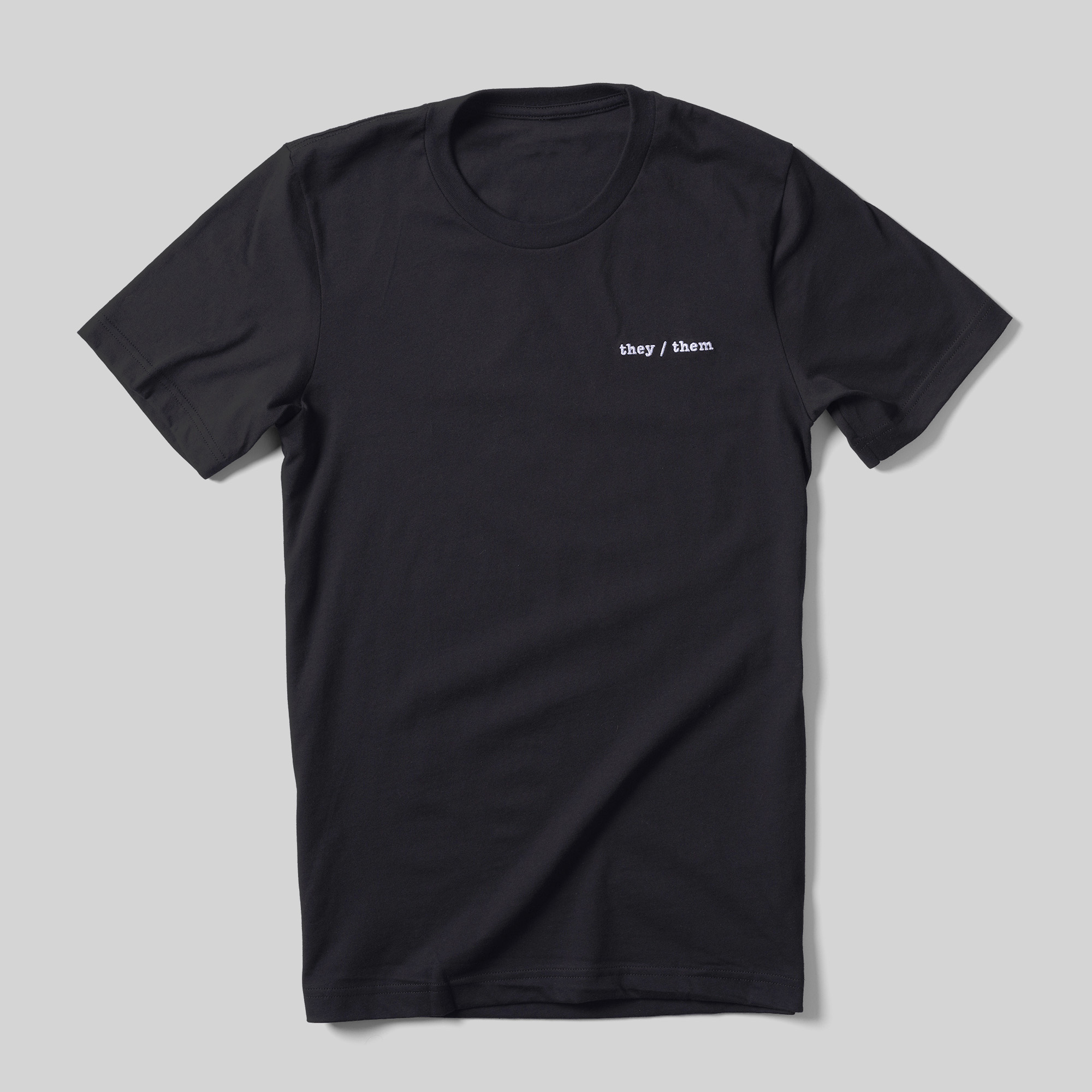 A black t-shirt with "they/them" printed on the left chest area.