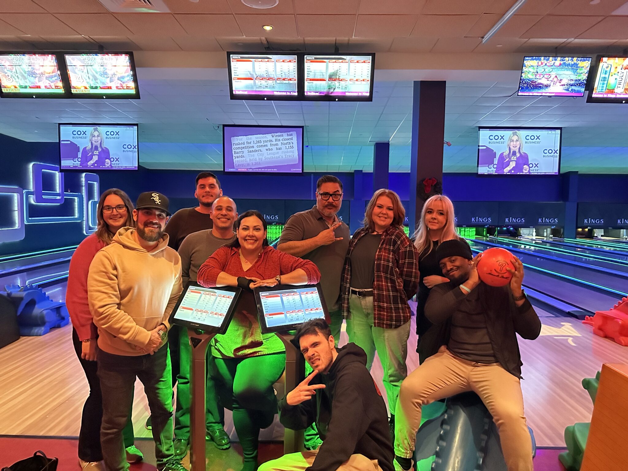 A large group of smiling people, including showroom manager Emilie Lalama, pose inside a bowling alley.