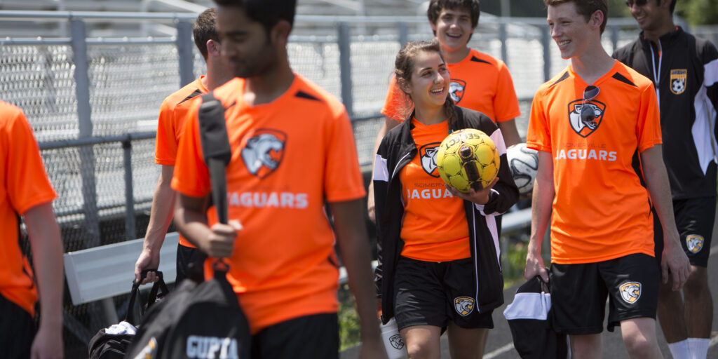 Somerville Jaguars high school soccer team walking together in matching custom orange and black jerseys with team logo
